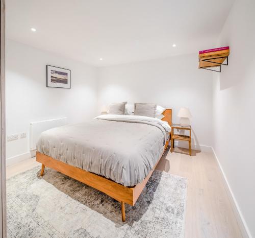 a white bedroom with a bed and a rug at Lowen Tree House in Truro
