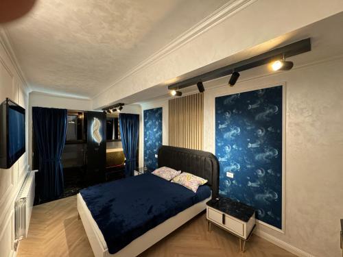 ein Schlafzimmer mit einem Bett und einer blauen Wand in der Unterkunft FancyLux Apartament in Suceava