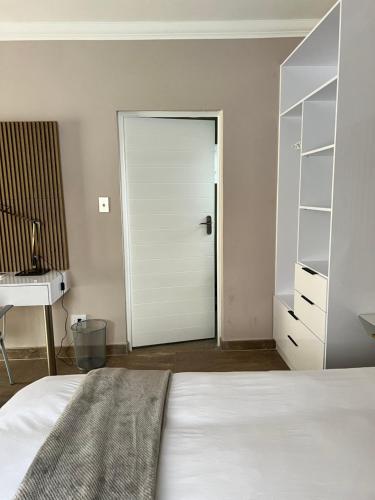a bedroom with a white door and a bed and a desk at Casero Guesthouse in Klerksdorp