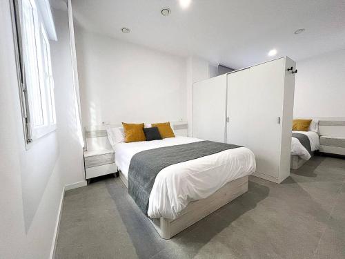 een witte slaapkamer met een groot bed met gele kussens bij Studio Alboránn in Málaga