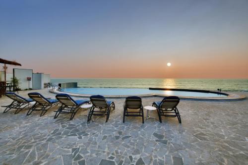 a group of chairs sitting around a pool on the beach at The Fern Leo Beach Resort , Madhavpur in Porbandar