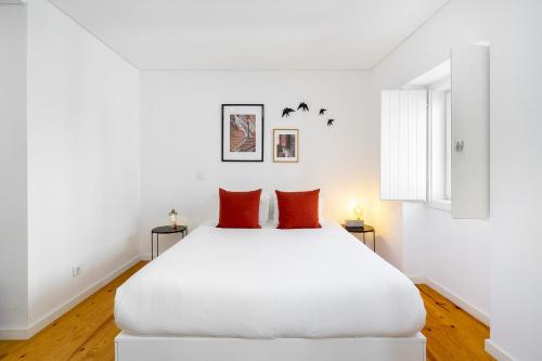 ein weißes Schlafzimmer mit einem großen weißen Bett mit roten Kissen in der Unterkunft Lisbon's Horizon Retreat: A View to Remember in Lissabon