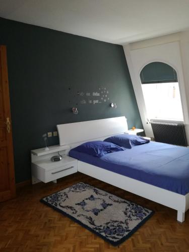 Schlafzimmer mit einem Bett mit blauer Decke in der Unterkunft "Côté cœur", charmant appartement au centre de Munster in Munster