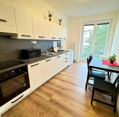 a kitchen with white cabinets and a table and a dining room at Centrum apartment in Brno