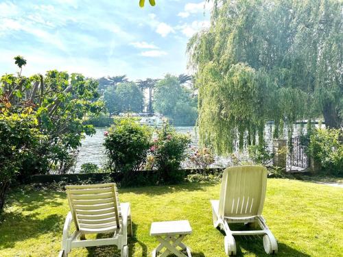 two chairs and a table in the grass at Sleeps 8 Thamefront Gem w PetsOK Free Parking in Staines