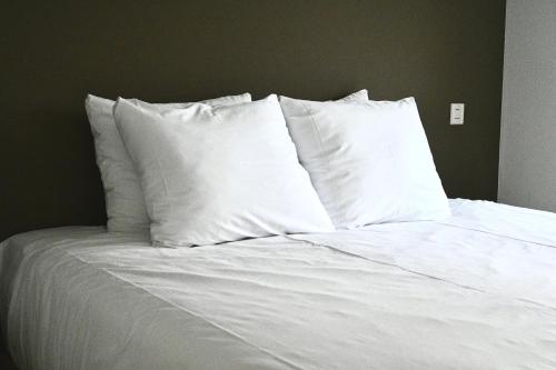 a bed with white sheets and pillows on it at De Viool Appartementen in Buren