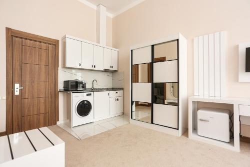 a kitchen with white cabinets and a washer and dryer at Chateau Milisi in Batumi