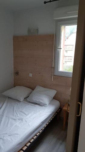 un petit lit dans une chambre avec une fenêtre dans l'établissement Appartement chaleureux Ski, Randonnées, Cures..., à Luchon