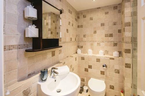 La salle de bains est pourvue d'un lavabo, de toilettes et d'un miroir. dans l'établissement Stylish & Peaceful Covent Garden Apartment, à Londres