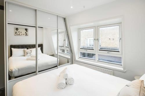 a bedroom with two beds and a mirror at Stylish & Peaceful Covent Garden Apartment in London
