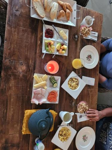 a wooden table with plates of food on it at Landhuis Belnem Bonaire in Kralendijk