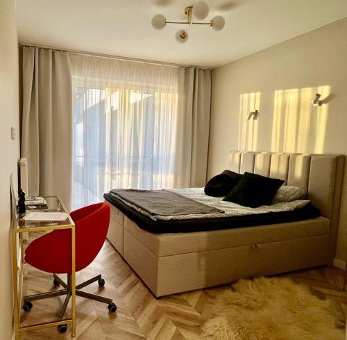 um quarto com uma cama com uma janela e uma cadeira vermelha em Apartament Twój ZDRÓJ & SPA Dr Duda em Busko-Zdrój