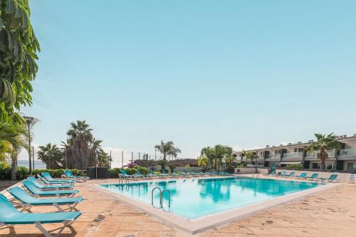 a swimming pool with lounge chairs in a resort at Relax Golf cerca de la playa in San Miguel de Abona