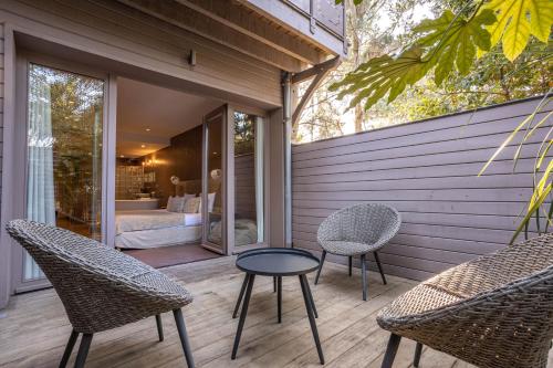 a patio with chairs and a table and a bed at Hôtel Côté Sable in Cap-Ferret