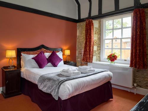um quarto com uma cama grande e almofadas roxas em Hitchin Priory Hotel em Hitchin