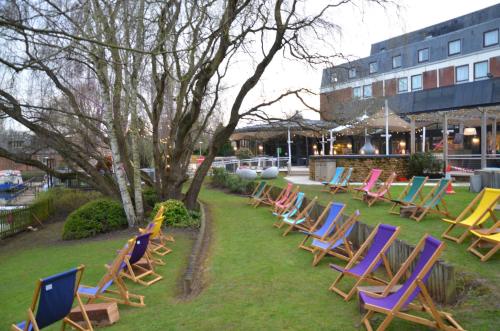 grupa krzeseł ogrodowych siedzących w trawie w obiekcie Crowne Plaza Stratford-upon-Avon, an IHG Hotel w mieście Stratford-upon-Avon