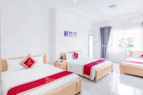 a white room with two beds and a window at Ngọc Sang 3 Hotel in Da Thanh