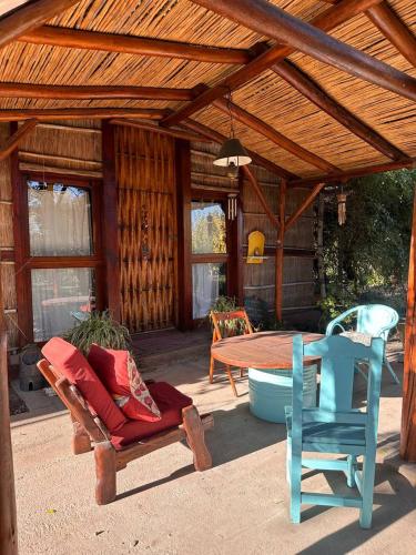 un patio con una mesa, sillas y un bosque en Eco-Hostel Lo de Lola en San Fernando del Valle de Catamarca