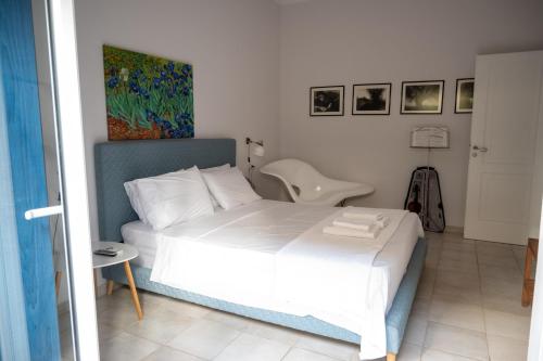 a bedroom with a white bed and a chair at Μονοκατοικία με κήπο στη θάλασσα. in Korinthos