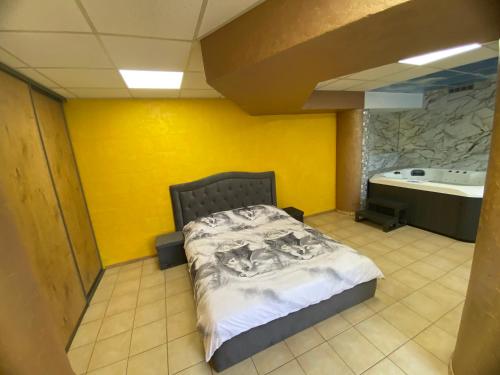 a bed in a room with a yellow wall at Jacuzzi in Klaipėda