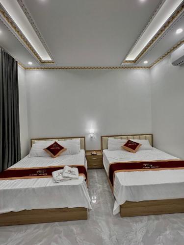 NẮNG HOTEL في Mù Cang Chải: سريرين في غرفة بجدران بيضاء