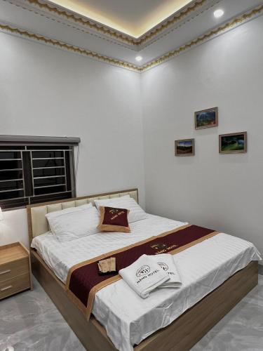 a bedroom with a bed with white sheets and a window at NẮNG HOTEL in Mù Cang Chải