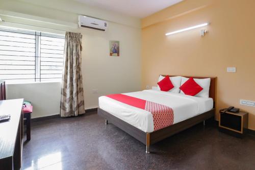 a bedroom with a bed with red pillows at The Olive Shine in Mysore