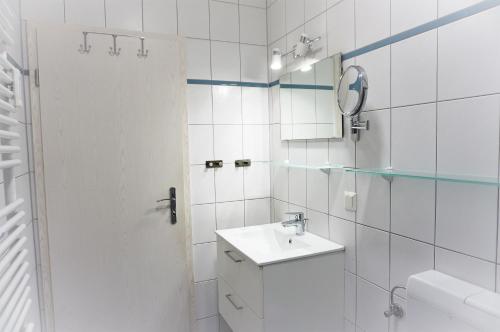 a white bathroom with a sink and a mirror at Villa Azur in Sassnitz