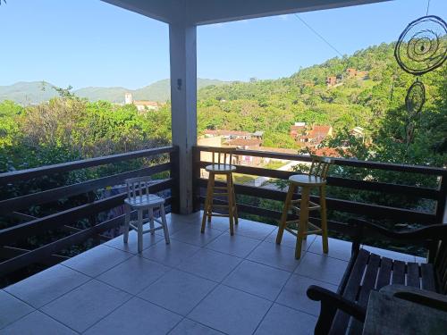 d'un balcon avec des chaises et une table offrant une vue. dans l'établissement Casa Vôo do Beija Flor, à Porto Belo