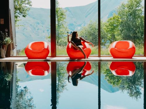 a woman sitting on a red swan chair in front of a window at Marco Polo Hotel Gudauri in Gudauri