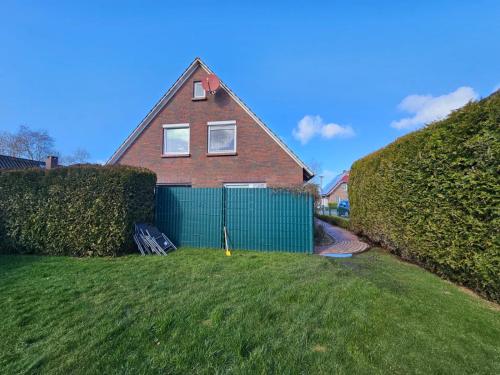 a house with a green fence in a yard at Ferienwohnung Huus Merle Booven in Neßmersiel
