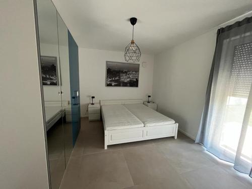 ein weißes Schlafzimmer mit einem Bett und einem Fenster in der Unterkunft Siegduo in Siegburg