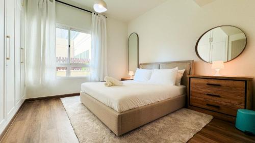 1 dormitorio con cama, espejo y ventana en Tranquil 1BR Garden Retreat Dubai Greens, en Dubái