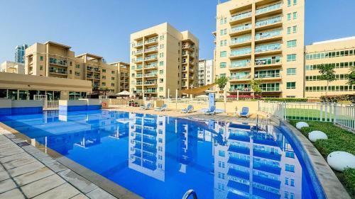 a swimming pool in front of some apartment buildings at Tranquil 1BR Garden Retreat Dubai Greens in Dubai
