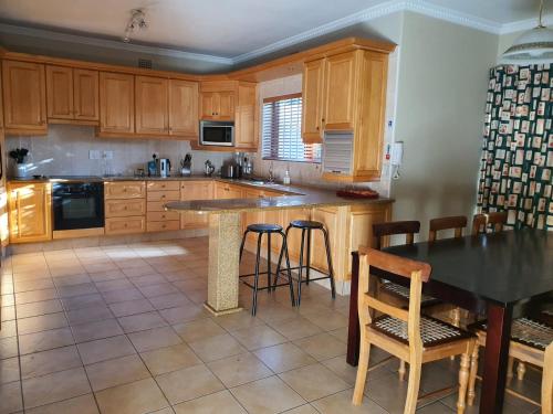 una cocina con armarios de madera, mesa y sillas en Ringwood Villa, en Ciudad del Cabo