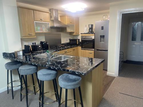a kitchen with a counter and bar stools at GM247 Nice Accommodation Stays in Wigan