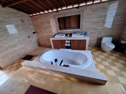a large bathroom with a tub and a toilet at Kori Maharani Villas & Resort in Keramas