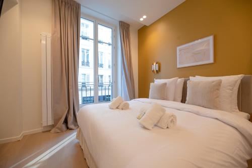 um quarto com uma grande cama branca e uma janela em CIA - Opera em Paris