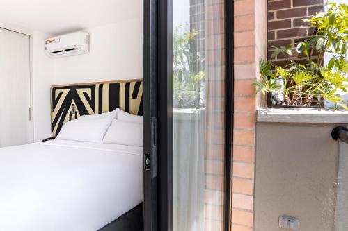 a bedroom with a bed and a window with plants at Origen Local Suites in Medellín