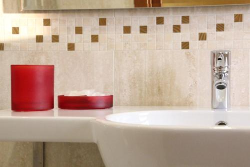 a bathroom sink with two red containers on it at Termini Beach Hotel & Suites in Lido di Jesolo