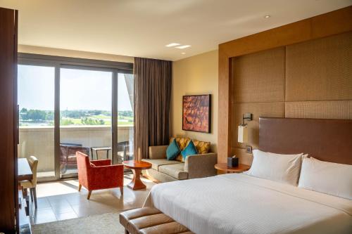 a hotel room with a bed and a living room at VOGO Abu Dhabi Golf Resort & Spa Formerly The Westin Abu Dhabi Golf Resort & Spa in Abu Dhabi