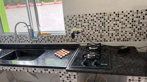 a kitchen counter with a stove and a sink at Chalé Orquidea in São Sebastião
