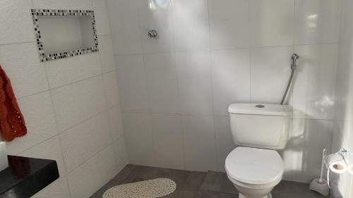 a white bathroom with a toilet and a shower at Chalé Orquidea in São Sebastião