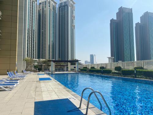 a swimming pool with blue chairs and tall buildings at Sea View Cozy 2BHK Al Reem 6ppl - more than 10 days stay free transportation from Abu Dhabi Airport- in Abu Dhabi