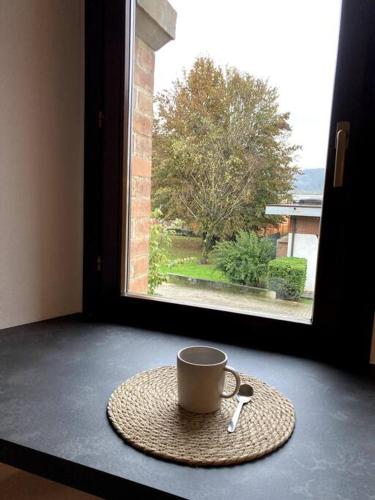 a cup and spoon on a table in front of a window at Residenza Le Fornaci in Sorisole