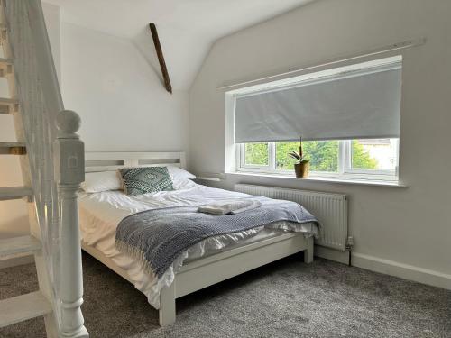 a white bedroom with a bed and a window at 2 Bedroom House in Bloxwich