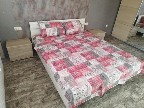 1 dormitorio con 1 cama con edredón rojo y blanco en Heart of Pernik apartment, en Pernik