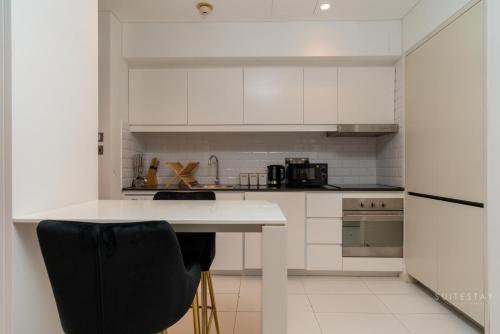 a kitchen with white cabinets and a black chair at Skyline Burj Facing Suite in Dubai