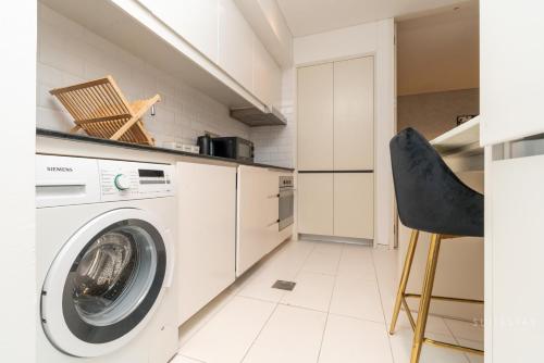 a laundry room with a washing machine and a chair at Skyline Burj Facing Suite in Dubai