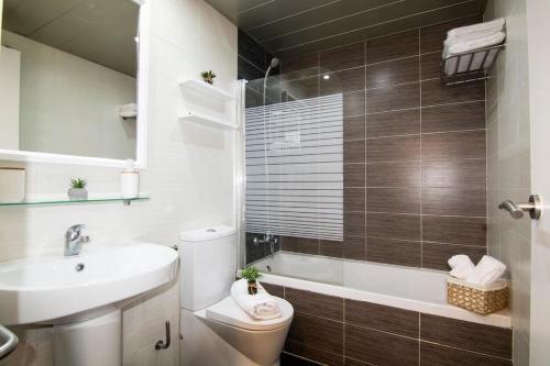 a bathroom with a toilet and a sink and a tub at SeaHomes Vacations - ACACIAS Beach&Chic in Lloret de Mar